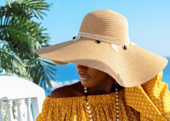 Portrait of beautiful African American model girl in stylish sun hat. Fashion black woman on natural background coast of sea. High quality photo