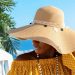 Portrait of beautiful African American model girl in stylish sun hat. Fashion black woman on natural background coast of sea. High quality photo