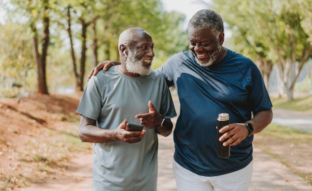 Two black senior friends walking together in public park