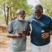 Two black senior friends walking together in public park