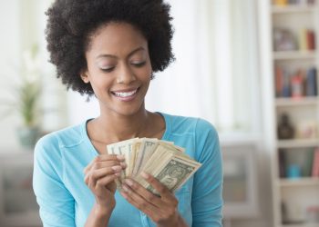African American woman counting money in living room