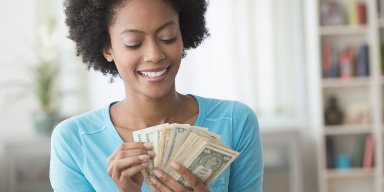 African American woman counting money in living room