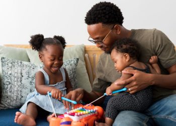 A man plays with his daughters on a xylophone toy