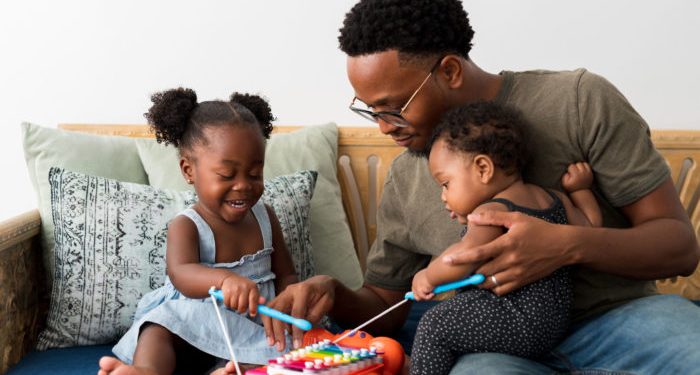 A man plays with his daughters on a xylophone toy